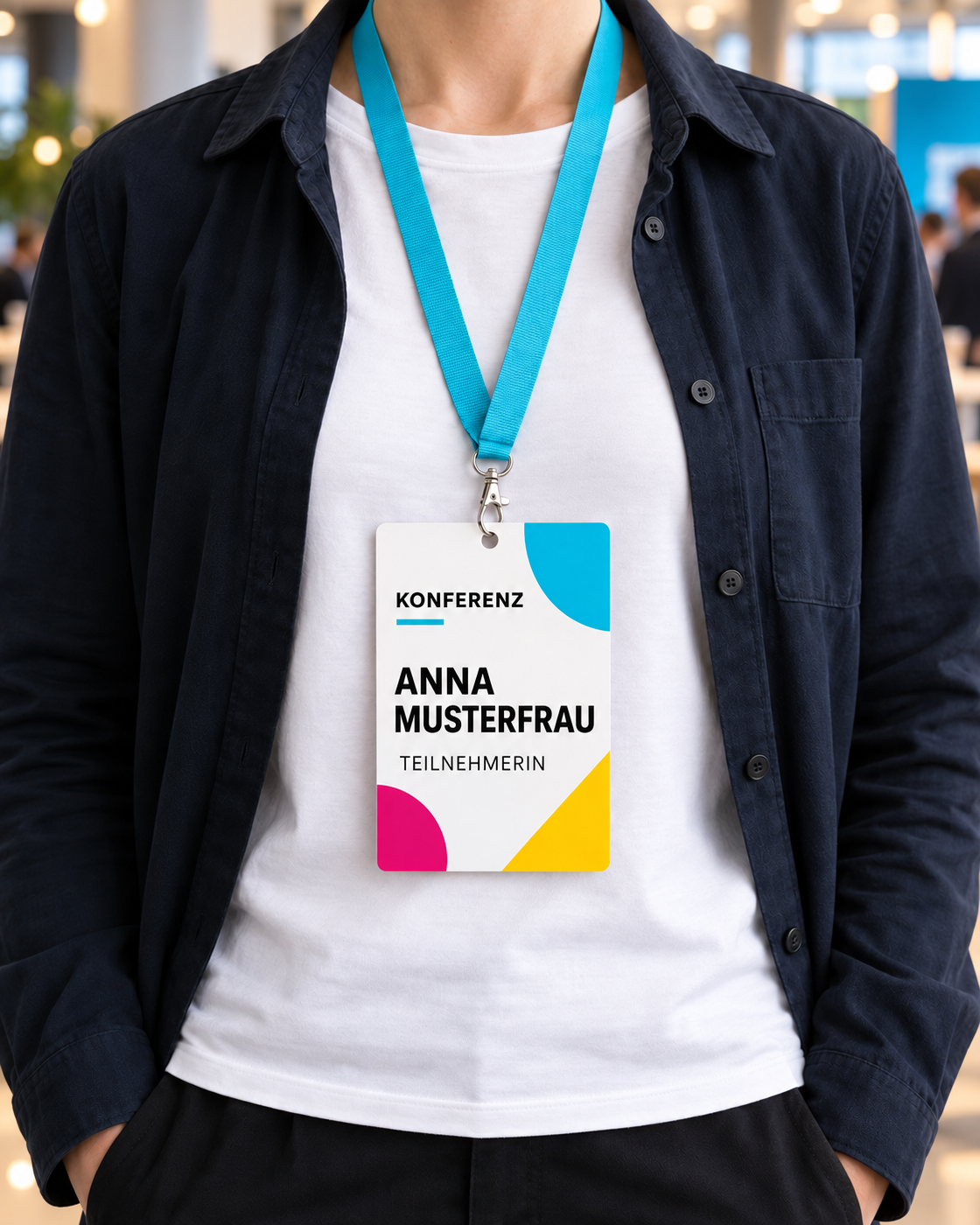 Oberkörper ohne sichtbares Gesicht mit dem Konferenz-Badge Anna Musterfrau am cyanfarbenen Lanyard vor unscharfer Eventumgebung