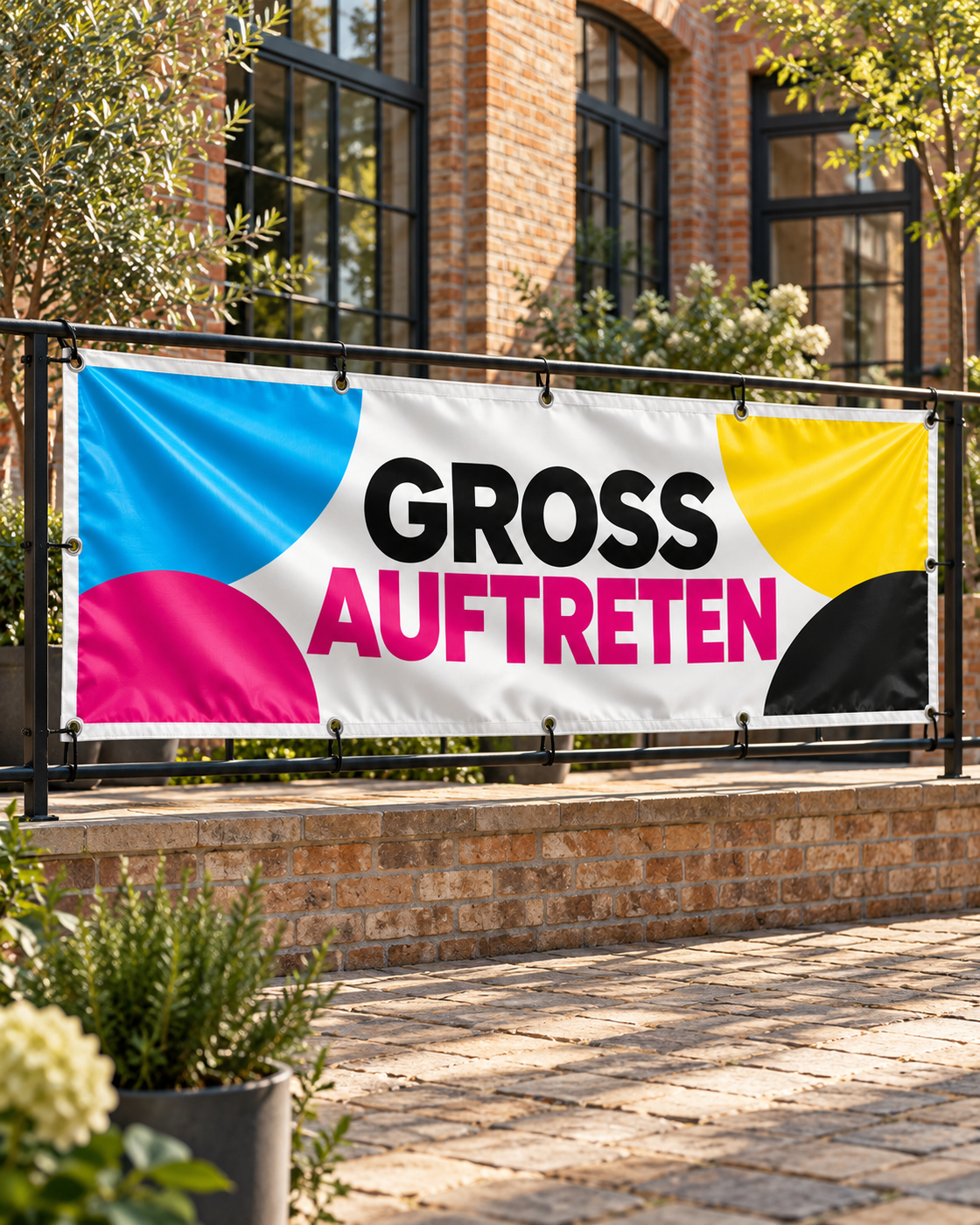 PVC-Banner mit Metallösen an einem schwarzen Geländer in einem begrünten Backstein-Innenhof