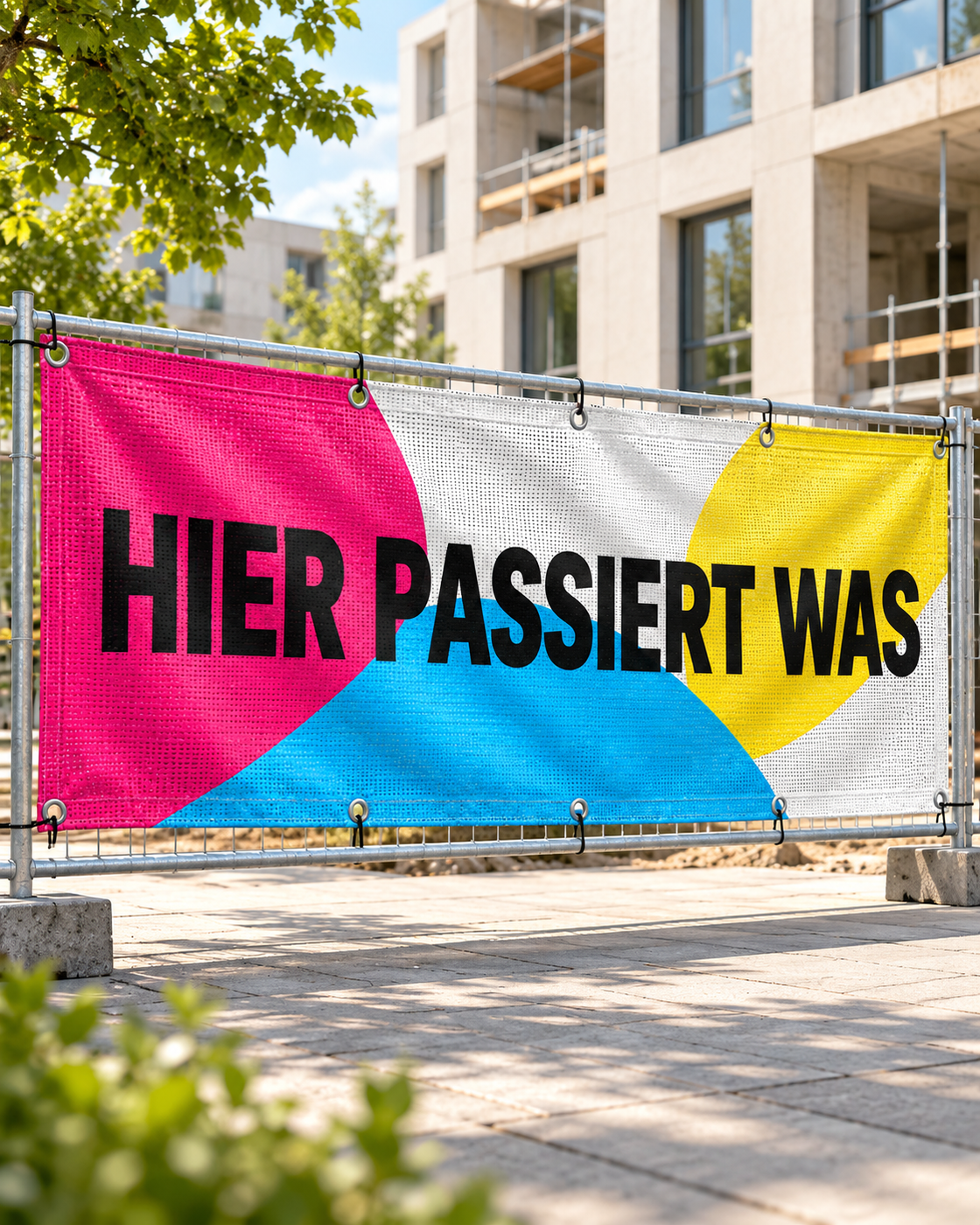 Bedrucktes Mesh-Banner mit Metallösen und Befestigungsschlaufen an einem Bauzaun vor moderner Architektur